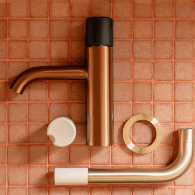 Copper and gold faucet set on a tiled wall background