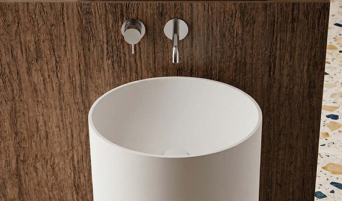 White freestanding sink in a bathroom setting with wooden vanity and terrazzo floor.